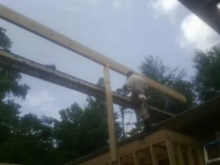 Carpenter setting a ridge beam over a new addition frame — Ice Dam Removal by Roofing Brothers in Garrett Park