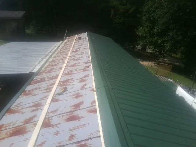 Old rusted panels beside newly installed green metal roofing — Wind Damage Roof Repair by Roofing Brothers in Garrett Park