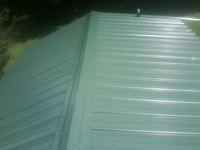 New green metal panels meeting at the ridge of a roof — Flat Roof Repair work by our crew in Garrett Park