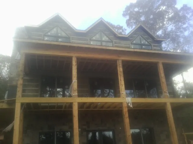 Dormers and porch framing on a large log home under construction — Roof Coating work by our crew in Garrett Park