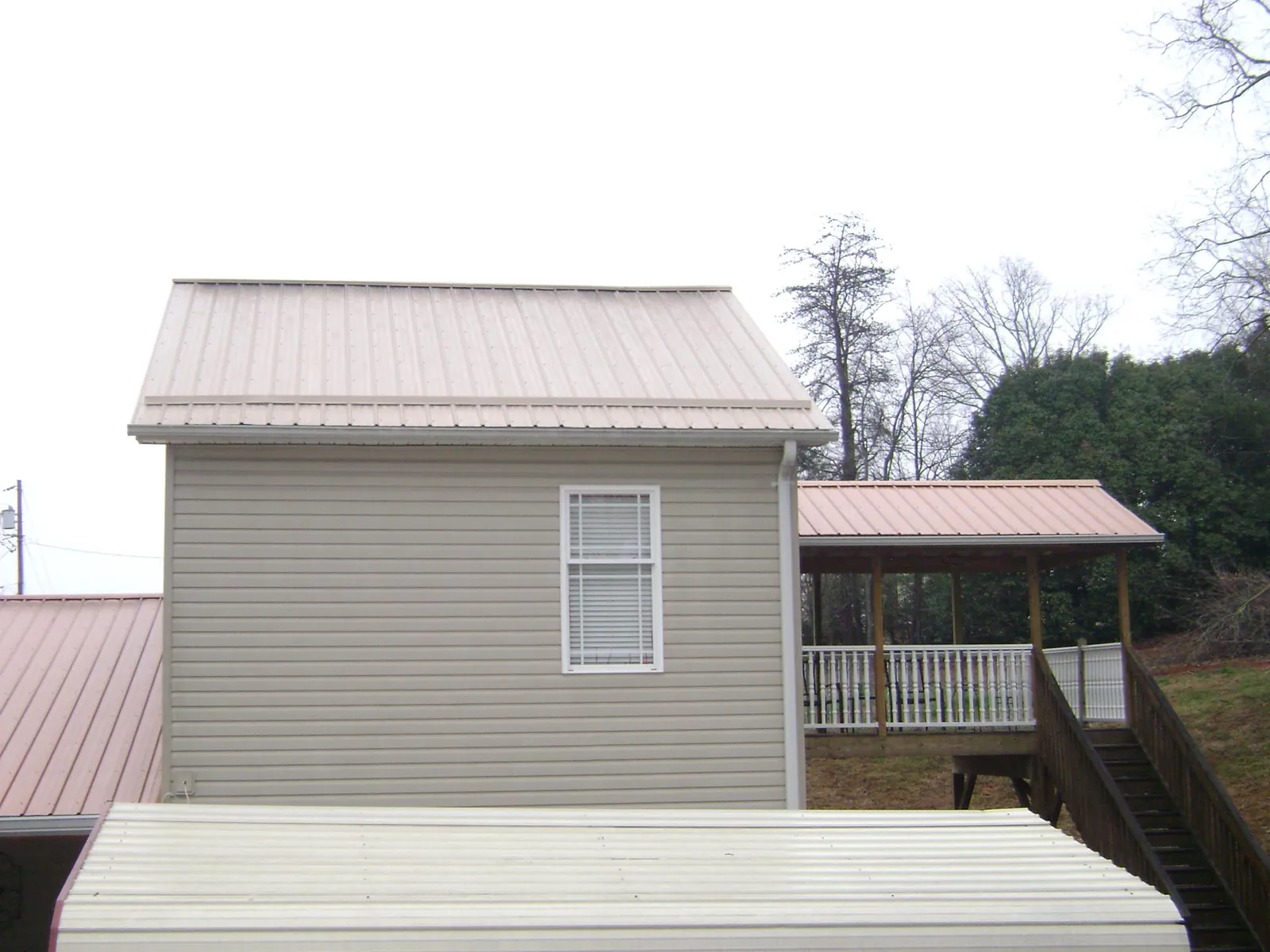 Tan metal roofs on a two story addition and attached porch, from a Roof Replacement job in Garrett Park