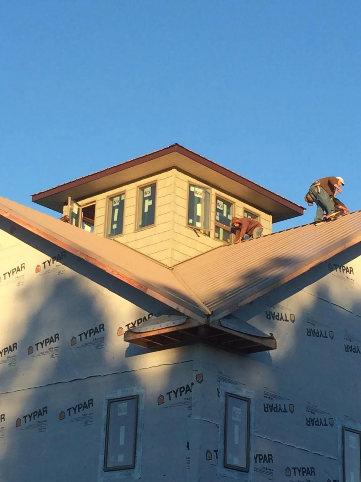 Roofers working around a rooftop cupola on a new metal roof at sunset — Roof Waterproofing in Garrett Park by Roofing Brothers